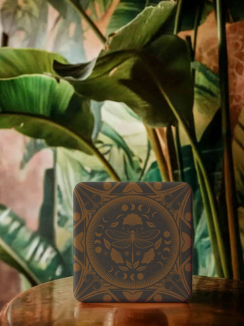 Square ceramic coaster featuring a detailed copper dragonfly design centered in a medallion, surrounded by moon phases and Art Nouveau patterns on a charcoal black background, with cork backing.